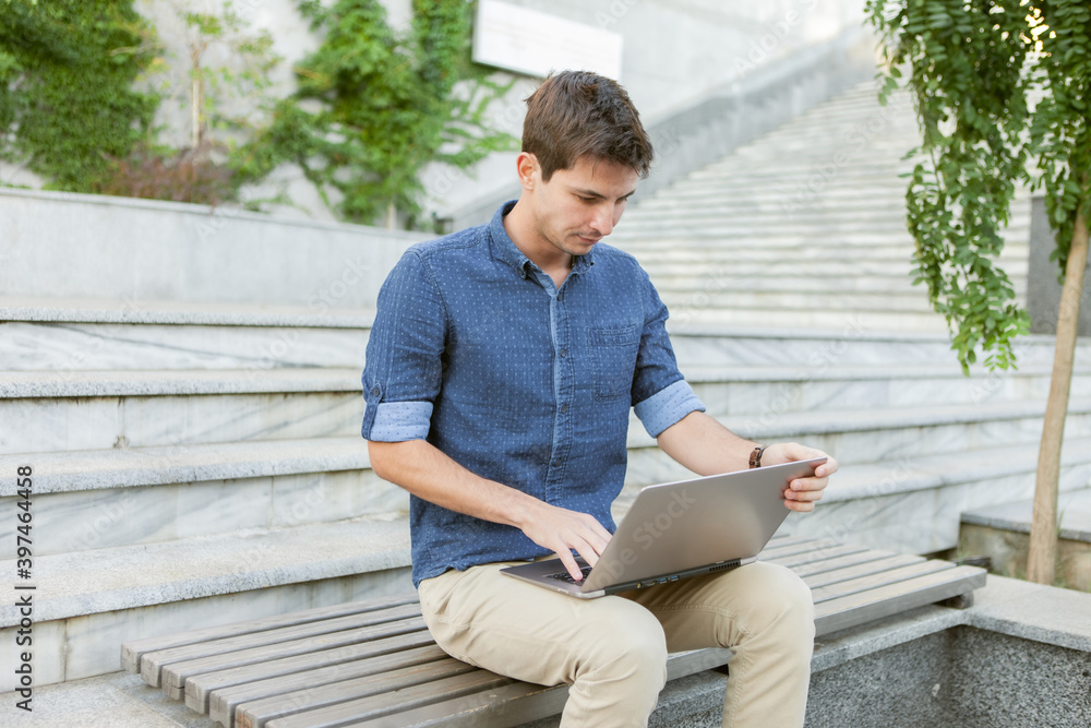 Young man student using laptop outdoors. Distance work or education concept Young man student using laptop outdoors. Distance work or education concept