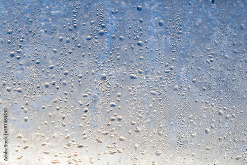 The texture of frozen drops of condensation on a transparent glass window. Water drops. Rain. Abstract texture background. A sharp cold snap, a frozen drop of water on the glass in winter