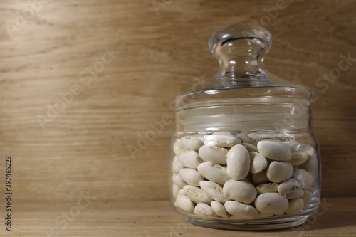 white beans in a glass jar with a lid on a bright wood background there is a copy of the spays photo