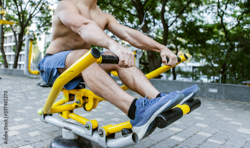 Muscular man is exercising on outdoor machines. Healthy lifestyle concept