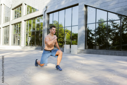 Young athletic man doing warm-up before outdoor workout. Healthy lifestyle. Fitness concept