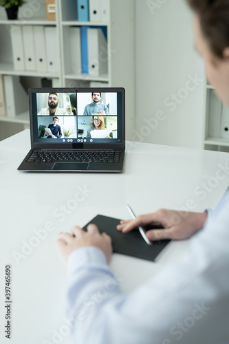 Several colleagues on laptop display looking at businessman sitting by desk