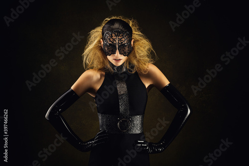 Portrait of a pretty young woman wearing fetish clothes and a lace mask