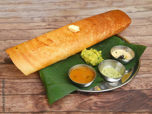 Butter Masala dosa, a south Indian traditional and popular crepe with filling of a mixture of mashed potatoes and fried onions, with a butter topping served with chutney and sambar, selective focus