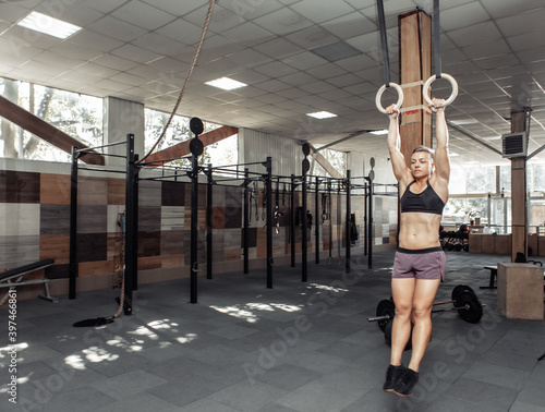 athletic sport woman exercising with gymnastics rings in modern cross gym