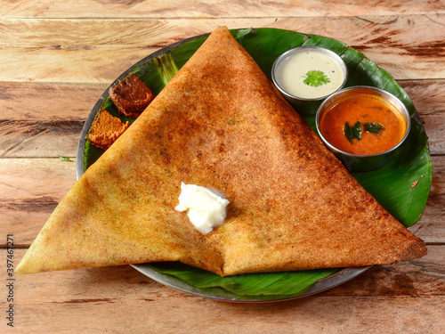 Mysore Masala dosa, a famous south Indian traditional breakfast with filling of a mixture of mashed potatoes served with different chutney and sambar over a rustic wooden background, selective focus photo