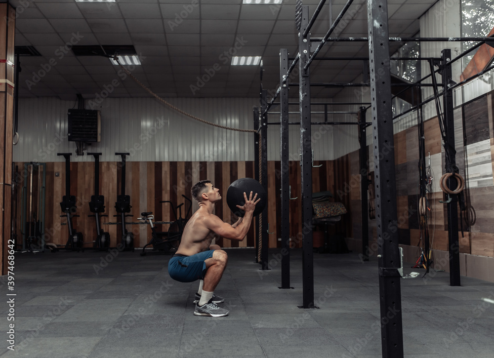 Athletic male bodybuilder exercises with medicine ball in the gym. Functional training Athletic male bodybuilder exercises with medicine ball in the gym. Functional training