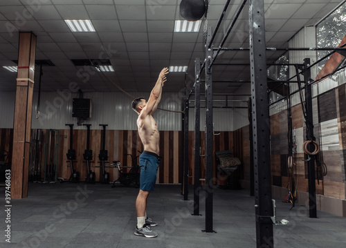 Athletic male bodybuilder exercises with medicine ball in the gym. Functional training