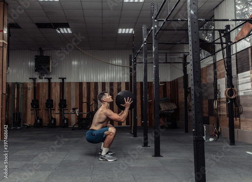 Athletic male bodybuilder exercises with medicine ball in the gym. Functional training