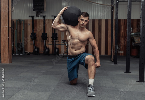 Athletic male bodybuilder exercises with heavy medicine ball in the gym. Functional training