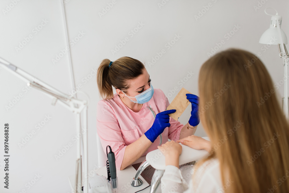 Female manicure master in a beauty salon work with hands of the client Female manicure master in a beauty salon work with hands of the client