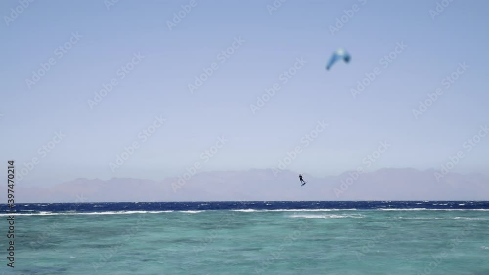 Acrobatic jump of professional kite surfer on the sea wave, athlete showing sport trick jumping with kite and board in air. Extreme water sport and summer vacations concept Acrobatic jump of professional kite surfer on the sea wave, athlete showing sport trick jumping with kite and board in air. Extreme water sport and summer vacations concept