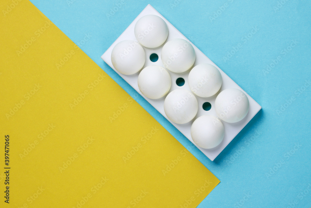 Tray with white chicken eggs on colored background. Minimalistic food concept. Top view Tray with white chicken eggs on colored background. Minimalistic food concept. Top view