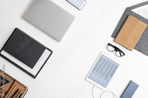 Flatlay of tablet, documents in clipboard, several notebooks in leather cover