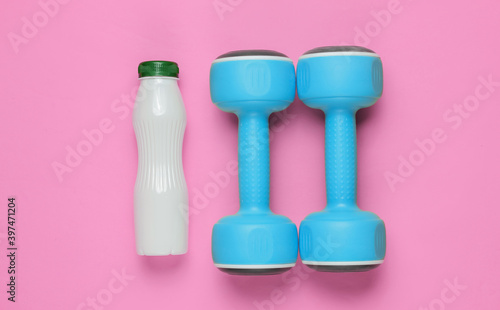 Minimalistic diet and sport concept. Dumbbells, bottle of yogurt on pink paper background. Top view © splitov27