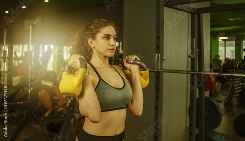 Athletic young fit woman doing exercise with kettlebells in the gym. Free weights, functional training