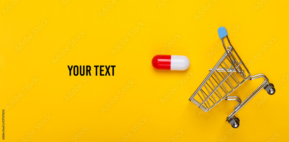 Mini shopping trolley, capsule tablet on yellow background with space for your text. Top view Mini shopping trolley, capsule tablet on yellow background with space for your text. Top view