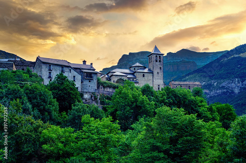 Rural landscape traditional architecture in the Pyrenees, mountain village at sunrise with high mountains and green trees. Torla Ordesa. 