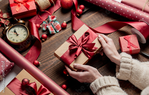 Woman wrapping gift on wooden table photo