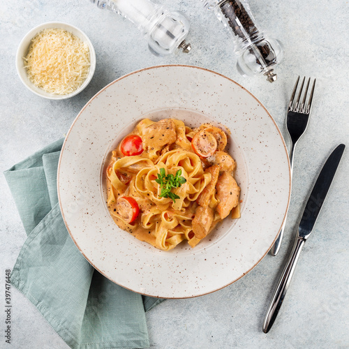 Pasta Tagliatelle with sauce and chicken fillet,fresh basil leaves in a white platel. light background. photo