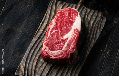 Foto Raw ribeye beef steak on a wooden cutting board . Top view.