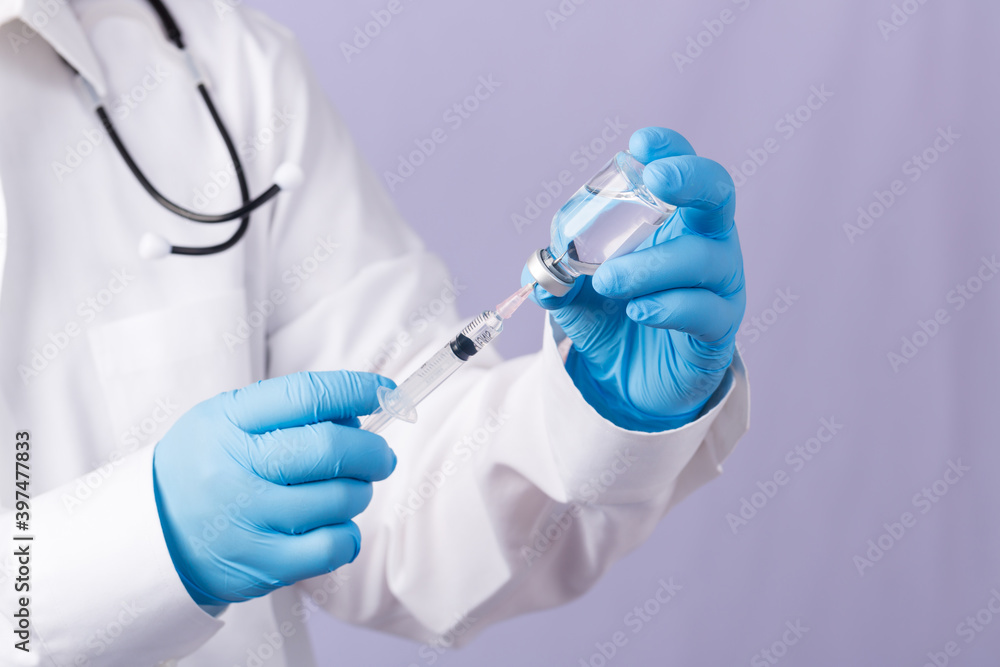 Doctor with a stethoscope on shoulder holding syringe and COVID-19 vaccine. Healthcare And Medical concept. Development and creation of a coronavirus vaccine COVID-19 . Coronavirus Vaccine. Doctor with a stethoscope on shoulder holding syringe and COVID-19 vaccine. Healthcare And Medical concept. Development and creation of a coronavirus vaccine COVID-19 . Coronavirus Vaccine.