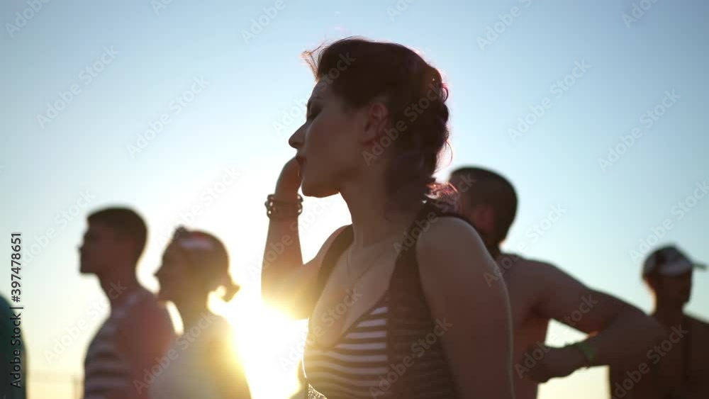 Pretty asian woman dancing at sunset light among the crowd of people at rock concert festival. Concept of youth culture and entertainment. Music fans enjoying summer gig. Pretty asian woman dancing at sunset light among the crowd of people at rock concert festival. Concept of youth culture and entertainment. Music fans enjoying summer gig.