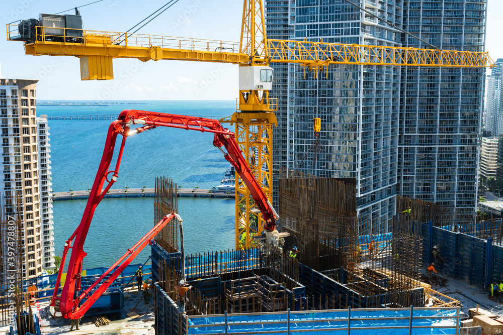 Tower crane and concrete hydraulic pump at work elevating a high rise to a new floor during contractor period of construction in brickell downtown Miami Florida USA