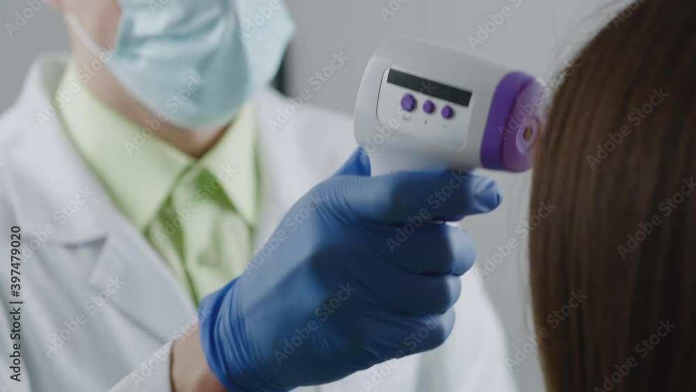 Healthcare worker male using a non-contact infrared thermometer to measure the temperature of an asymptomatic female patient of coronavirus covid19 Healthcare worker male using a non-contact infrared thermometer to measure the temperature of an asymptomatic female patient of coronavirus covid19