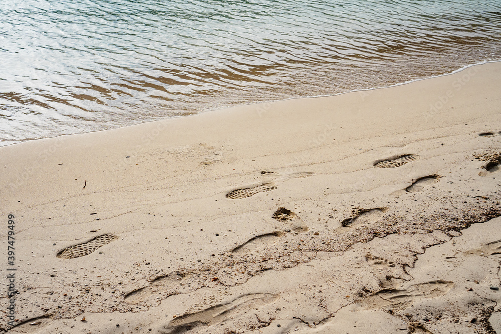 Footprints in the sand, near the shore, with calm waters beach, in Minorca Footprints in the sand, near the shore, with calm waters beach, in Minorca