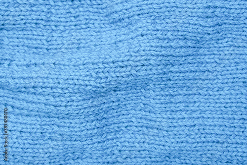 Crumpled knitted blue fabric background, waved and twisted, curved turquoise woolen knitwear