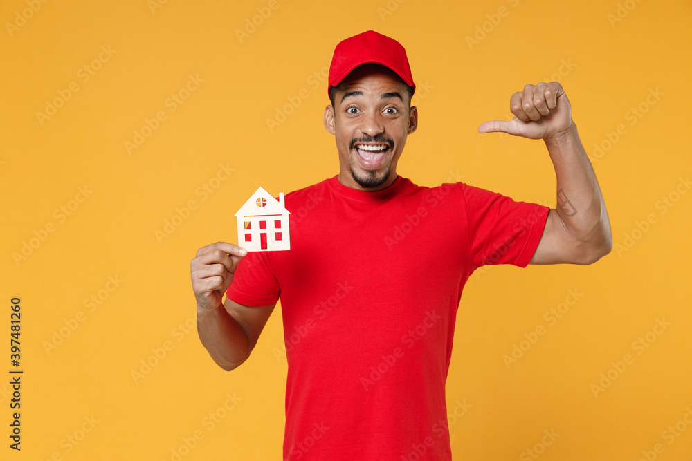 Delivery employee african man 20s in red cap blank print t-shirt uniform workwear work courier dealer service during quarantine coronavirus covid-19 virus concept isolated on yellow background studio. Delivery employee african man 20s in red cap blank print t-shirt uniform workwear work courier dealer service during quarantine coronavirus covid-19 virus concept isolated on yellow background studio.