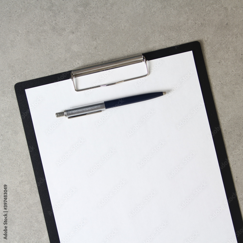 Template of white paper with a ballpoint pen on light grey concrete background in a black tablet with a clip. Concept of new idea, business plan and strategy, with empty space for text Template of white paper with a ballpoint pen on light grey concrete background in a black tablet with a clip. Concept of new idea, business plan and strategy, with empty space for text
