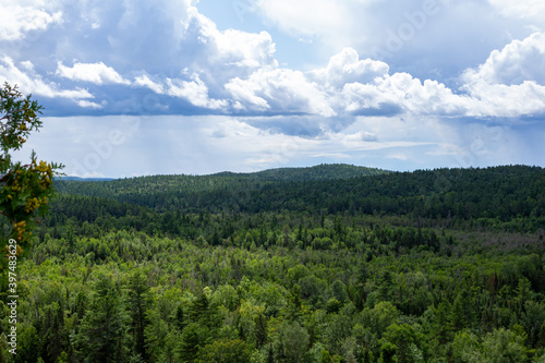 Landscape of green forest hills below clouds