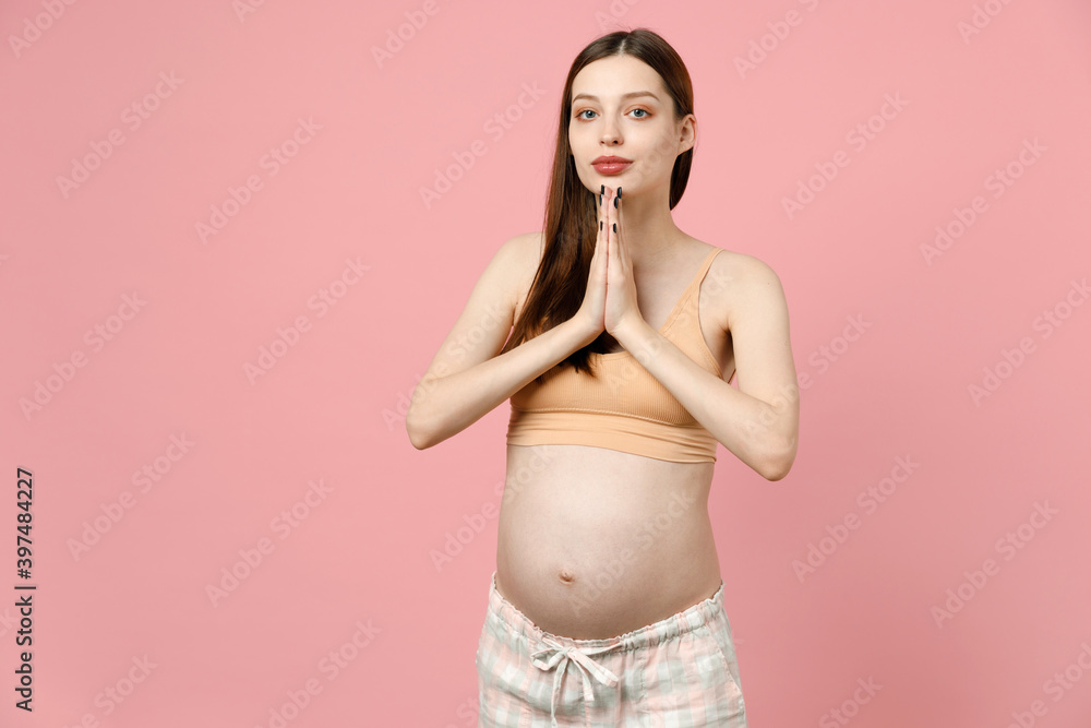 Happy young pregnant woman future mom in basic top stroking keeping hands folded, belly stomach tummy with baby isolated on pastel pink background studio Maternity family pregnancy gynecology concept Happy young pregnant woman future mom in basic top stroking keeping hands folded, belly stomach tummy with baby isolated on pastel pink background studio Maternity family pregnancy gynecology concept