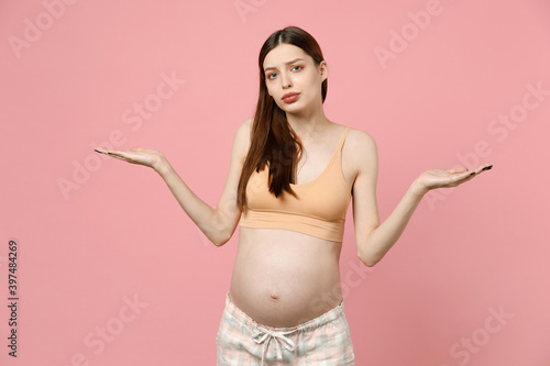 Tired sad young pregnant woman future mom in basic top stroking keeping hands on belly stomach tummy with baby isolated on pastel pink background studio. Maternity family pregnancy gynecology concept. © ViDi Studio