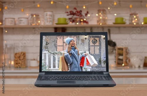 Happy beautiful girl with shopping bags in her hands against the background of the Christmas house on the monitor screen . Christmas, x-mas, shopping, sale, gifts, concept.Safe Online shopping!
