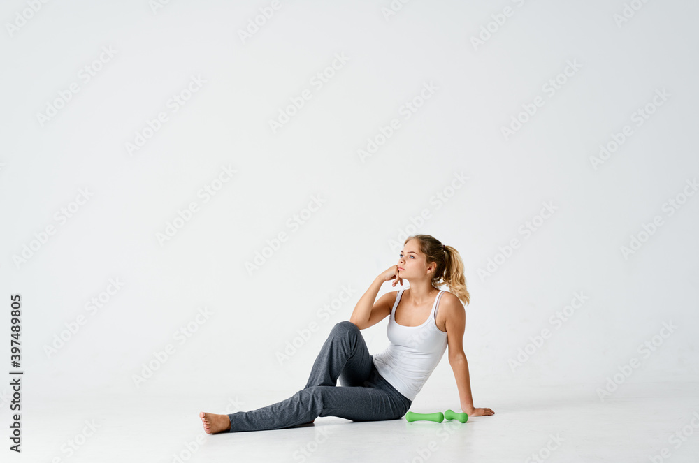 cute woman seroshtanov sits on the floor and a dumbbell in the background Copy Space cute woman seroshtanov sits on the floor and a dumbbell in the background Copy Space