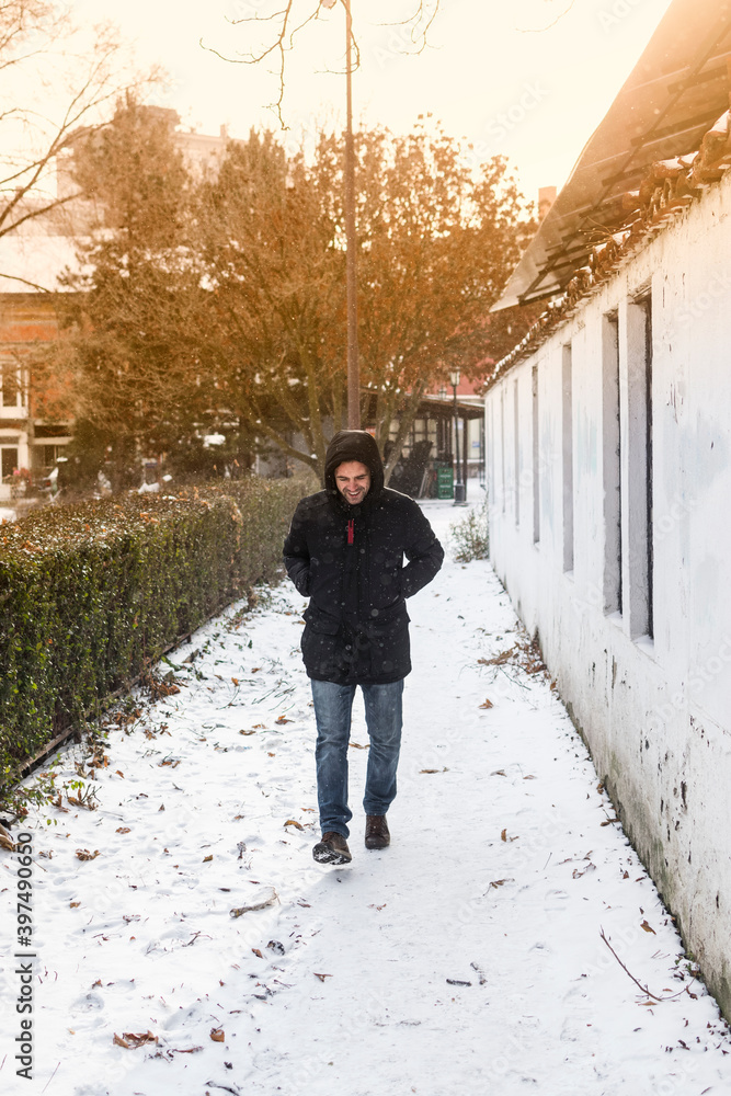 Young man walking in small alley covered with snow