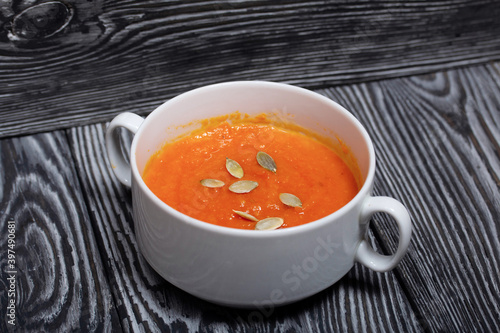 Pumpkin tomato cream soup. With the addition of pumpkin seeds. On pine boards.
