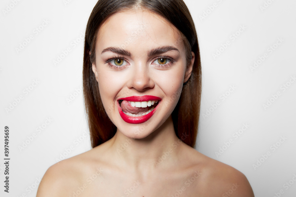 Woman with bared shoulders red lips showing tongue grimace studio Woman with bared shoulders red lips showing tongue grimace studio