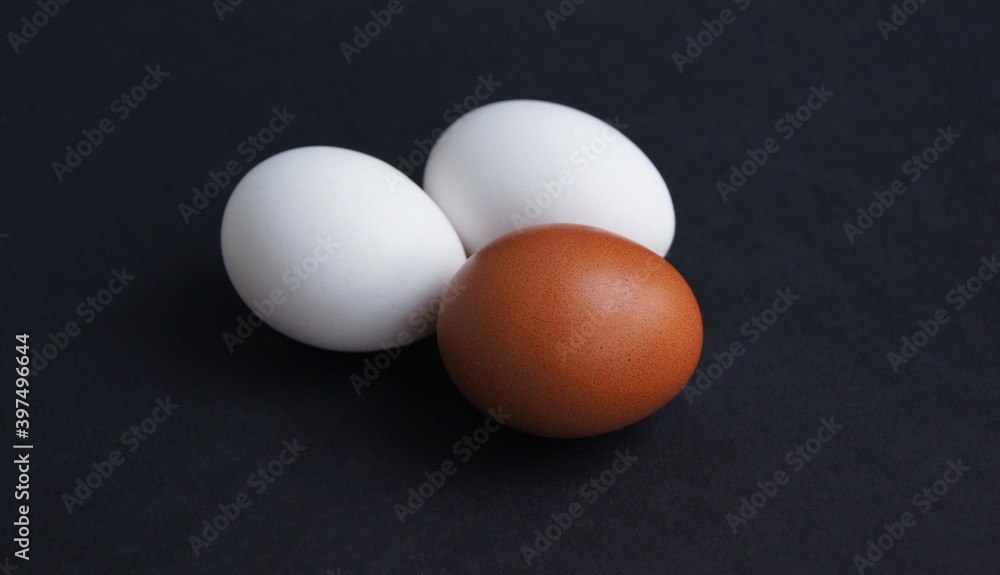 Chicken or turkey eggs of different brown and white colours on black background.Three eggs closeup and top view Chicken or turkey eggs of different brown and white colours on black background.Three eggs closeup and top view