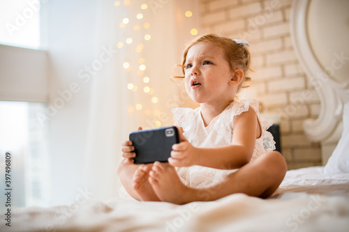 view on little girl with displeased expression holding mobile phone