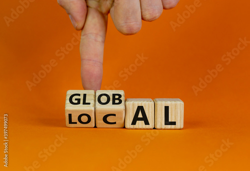 Local or global symbol. Hand turns cubes and changes the word 'local' to 'global'. Beautiful orange background. Business and local or global concept. Copy space. photo