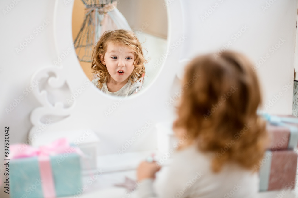 reflection in the mirror of little cute girl with surprised expression on her face reflection in the mirror of little cute girl with surprised expression on her face