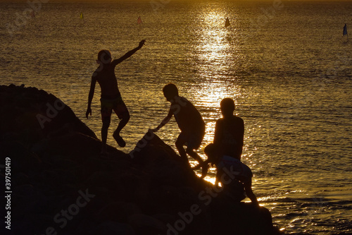 Children playing on the ocean rocks at sunset in Hawaii