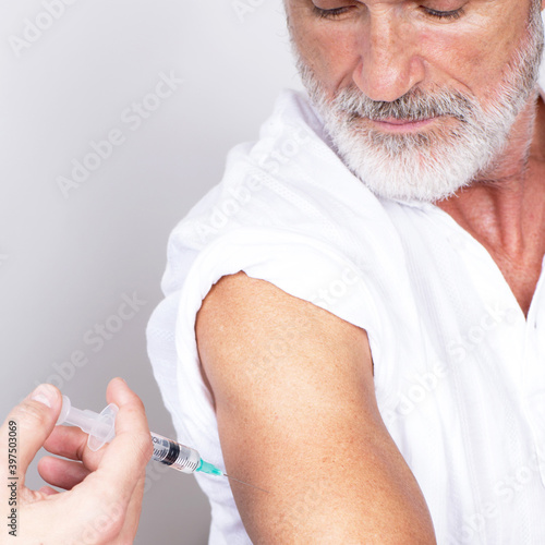 Setting an coronavirus vaccine in the arm of an elderly man with grey beard
