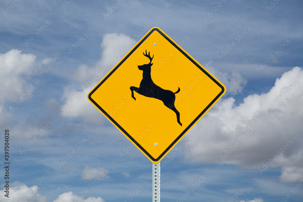 Deer crossing sign on blue sky background (North American road sign