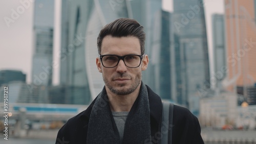 Photography Man in eyeglasses on background of business skyscrapers, looking at the camera