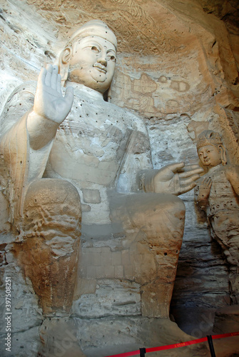 Yungang Grottoes near Datong in Shanxi Province, China. Large ancient statue of Buddha in a cave at Yungang. Portrait view from side. Yungang Buddhist cave art and sculptures UNESCO world heritage.